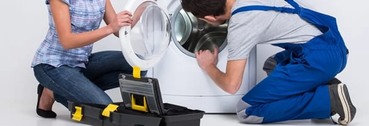 Washer repair technician inspecting a front-load washing machine with tools in Jersey City, NJ