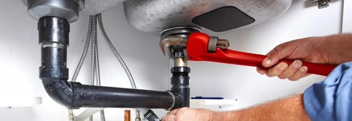 Garbage disposal repair technician tightening the sink drain and disposal connection in Jersey City, NJ