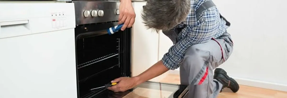 Oven repair technician inspecting and servicing an electric oven in Jersey City, NJ