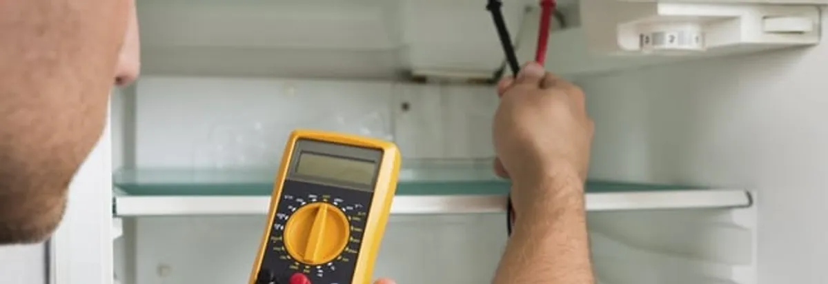 Refrigerator repair technician testing electrical components with a multimeter in Jersey City, NJ