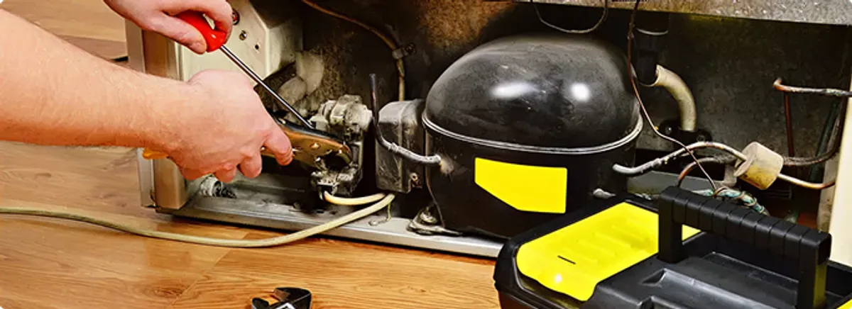 Refrigerator repair technician fixing the compressor and wiring in Jersey City, NJ