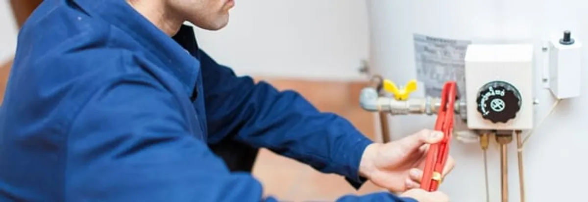 Water heater repair technician adjusting the temperature control and gas valve in Jersey City, NJ